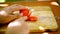 Female hands sliced tomato on a wooden board.