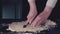 Female hands slicing dough for pasta by vintage roll over black table, powdering by flour. Dark rustic style. In retro