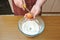 Female hands smash the chicken egg with a knife over a bowl of wheat flour in the kitchen