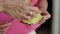 Female hands smear a green paste with a knife on the toast, close-up