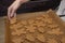 Female hands spread Christmas cookies on a baking sheet to bake. Selective focus