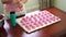 Female hands squeeze rows of berry marshmallows on a baking paper