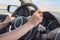 Female hands on the steering wheel of a car while driving