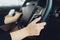 Female hands on the steering wheel of a car while driving. sunset the background, the windshield and road.