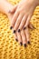Female hands with stylish color nails on knitted fabric, closeup