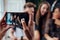 Female hands taking photo with smartphone of young cheerful friends, blurred background