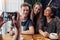 Female hands taking photo of smiling group of friends drinking tea in a cozy coffee house with smartphone