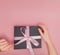 Female hands unpacking gift box. Female manicured hands going untied gift box with pink bow. Holiday and celebration concept