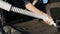 Female hands vacuuming car trunk with vacuum cleaner removing dirt and dust from car trunk outdoors at sunset