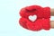 Female hands in warm red crocheted mittens with snowy heart. Whi