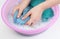 Female hands washing blue clothes in pink basin