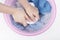 Female hands washing white and blue clothes with foam in basin, top view