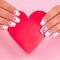 Female hands with white manicure nails, hearts design