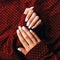 Female hands with white manicure on a terracotta fabric background