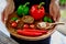 Female hands with a wooden tray with fresh cherry tomatoes, garlic cloves, chili peppers, basil leaves, red and green capsicums, m