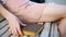 Female hands write a message on smartphone and takes a book outdoors on the bench