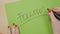 Female hands writing follow in capital letters and underlining it on a green paper using a black marker -