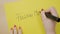 Female hands writing follow in capital letters on a yellow paper using a black marker -