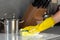 Female hands in yellow gloves cleaning electrical stove with a sponge