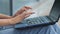 Female hands of young woman typing text message on laptop lying on girls lap f in jeans, close-up. Graceful fingers of