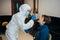 Female health Professional in PPE, face mask and shield, taking a Covid-19 test at patient`s house