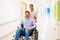 Female Healthcare Worker With Patient On Wheelchair At Hospital