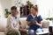 Female healthcare worker sitting with a senior Hispanic man in his living room during a home visit