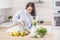 Female on a healthy diet chopping fruits to a blender for a raw food mixed snack