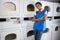 Female Helper Leaning On Dryers In Laundry