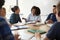 Female High School Tutor Sitting At Table With Pupils Teaching Maths Class