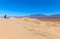 A female hiker makes descent on a trail to the bottom of the dunes in Mojave Preserve on a windy morning.