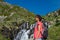 Female hiker near wild splashing waterfall