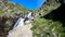Female hiker near wild splashing waterfall. Ayous lake french Pyrenees