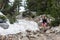 Female hiker poses next to a patch of snow still leftover on a hiking trail in the Sierra Nevada mountains of California in Little