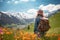 Female hiker standing in flowering alpine meadow and admiring a scenic view from a mountain top. Adventurous young girl with a