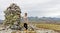 Female hiker standing next to stone cairn