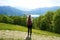 Female hiker standing on the trail and looks with satisfaction from the top of mountain the lake