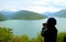 Female hiker taking photo of the scenic panoramic view of Jinvali water reservoir, Aragvi river, Georgia