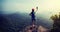 Female hiker taking photo stand on cliff edge