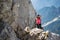 Female hiker taking a picture with her phone on a rocky, scrambling trail, in the Julian Alps, Triglav National Park, Slovenia