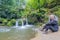 Female hiker tourist sitting on rock, SchiessentÃ¼mpel waterfall on Black Ernz river