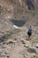 Female hiker walks along the trail of rocky scree and talus along the 20 Lakes Basin area of California mountains