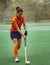 Female hockey player exercising on a grass field