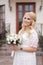 Female hold bouquet of white roses in hands. Mini wedding. Blond hair bride with bouquet of flowers