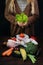 Female holding fresh salad among organic healhty food in plastic free eco bags over black background. Waste free