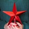 Female holding in hand christmas red star for tops chistmas tree. Close up. Merry christmas. Christmas JOY.