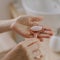 Female holding pink quartz roller for face massage while doing beauty morning routine in bathroom