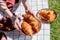 Female holding a plate with croissants over cake and checked litter on green grass.