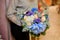 Female holds a bouquet with blue and white hydrangeas, beige roses and succulents