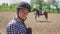 Female horse rider wearing a helmet smiling at the camera Horse In The Background
